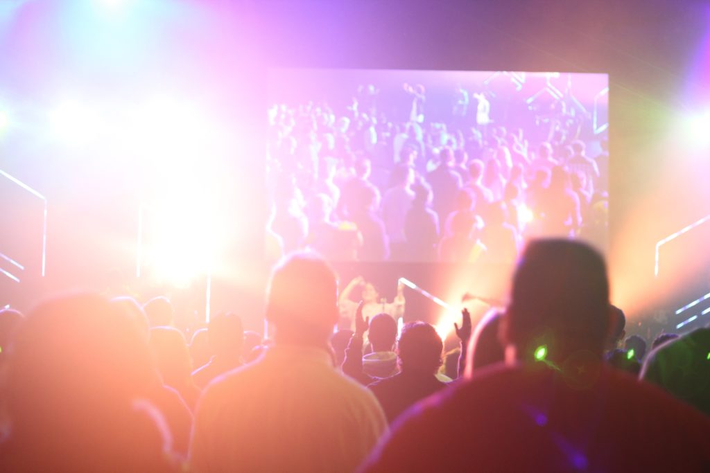 people at a concert with a large screen